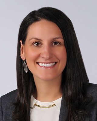 A woman in a suit and earrings is smiling for the camera.