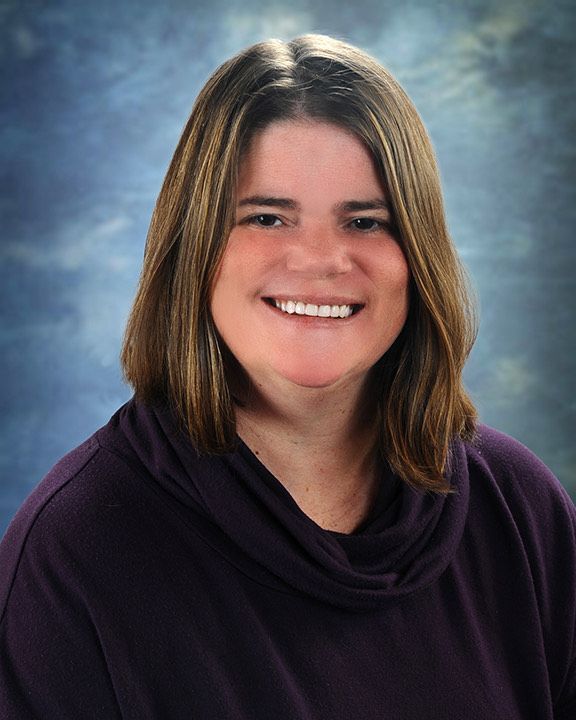 A woman wearing a purple sweater smiles for the camera