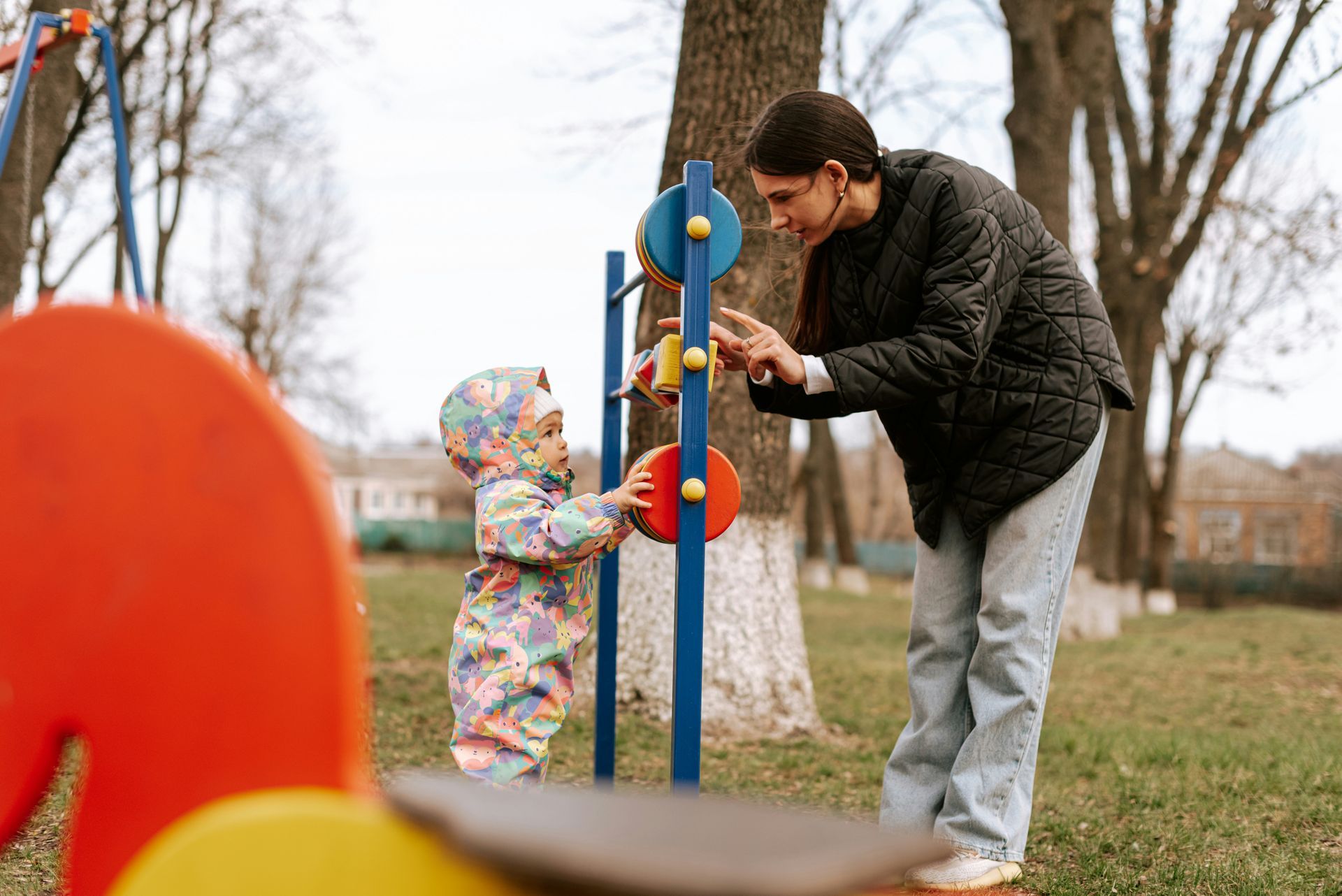 A woman is playing with a baby in a park.